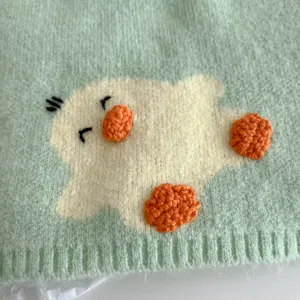 Close up of cute duck embroidered knit scarf detail showcasing soft texture and cozy winter style.