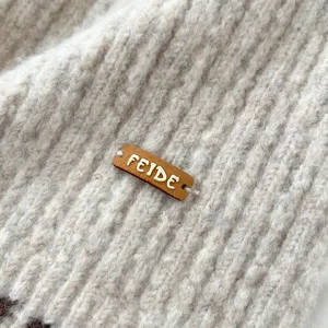 Detalle de bufanda de punto beige con textura acanalada cómoda y elegante etiqueta de cuero.