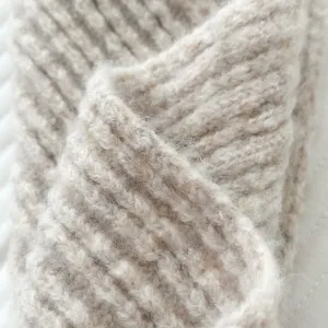 Primer plano de bufanda de punto acanalado beige suave con textura cálida de invierno.