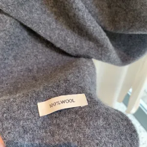Close up detail shot of pure grey wool fabric material showing 100 percent wool label texture.