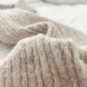 Detalle de bufanda de punto acanalado beige, textura suave y accesorio de invierno cálido.