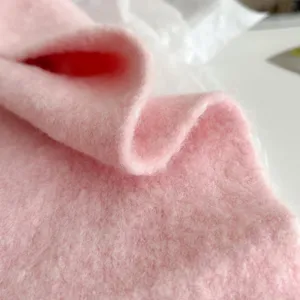 Dettaglio sciarpa in maglia rosa, consistenza morbida e calda scaldacollo invernale primo piano.