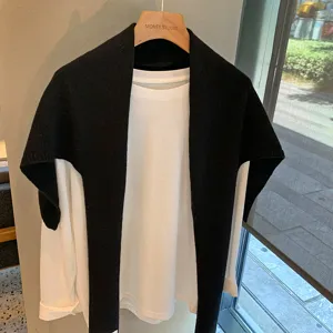 Chal de punto negro combinado con camiseta blanca de manga larga, estilo casual versátil.