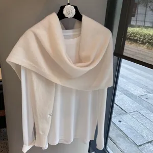 Detailed view of women solid color knitted shawl paired nicely with a white shirt.