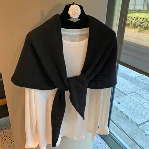 Detailed shot of black knit triangular scarf shawl with white long sleeve t-shirt on hanger