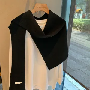 Bufanda chal de lana negra combinada con top blanco de manga larga, detalle punto de invierno.