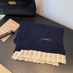 Close-up detail of navy blue knit winter scarf featuring delicate white lace ruffle trim.