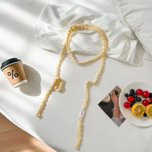 Close-up of handmade yellow crochet knitted neck chain scarf, soft fabric detail.
