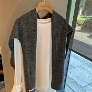 Vista detallada de chal de lana gris oscuro acogedor con camiseta blanca de manga larga.
