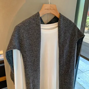 Detalle de chal de punto gris textura acogedora, look en capas elegante para atuendos de otoño.