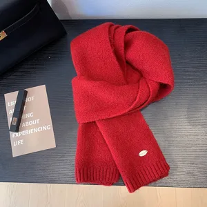Primer plano detallado de una bufanda de invierno tejida en rojo suave con etiqueta de metal fina.