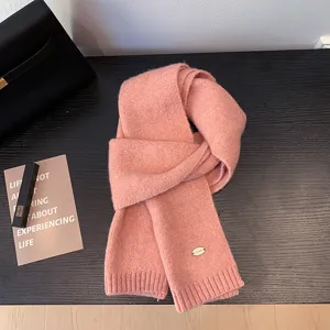Vista detallada de una bufanda de invierno rosa suave, muy cálida y elegante con etiqueta metálica.