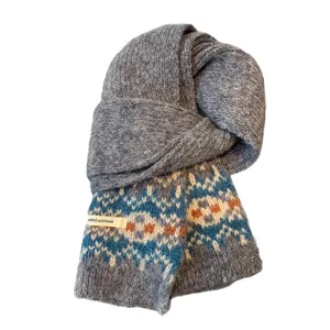 Cozy grey knit winter scarf featuring traditional Fair Isle geometric patterns and warm styling.