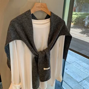 Detalle bufanda lana gris acogedora, chal drapeado casual sobre parte superior, invierno.