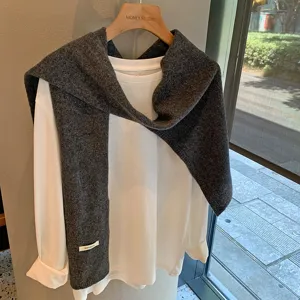 Vista detallada de un elegante chal de lana gris combinado con una parte superior.