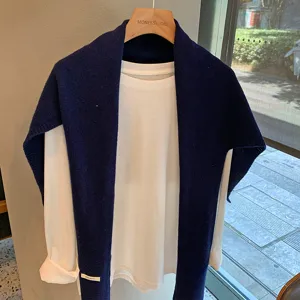 Vista detallada de un elegante chal de lana azul oscuro sobre una camiseta blanca.