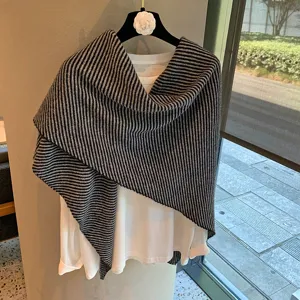 Primer plano del chal triangular de punto a rayas blancas y negras con fina textura de lana suave