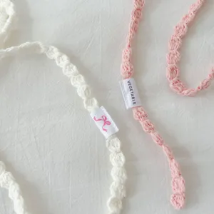 Close-up of handmade crochet knitted necklace with delicate woven texture and cute label.