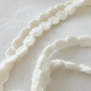 Detailed closeup of handmade white crochet flower choker necklace, delicate knit texture accessory.