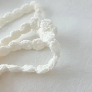 Handcrafted crochet flower necklace detail, white knitted skinny scarf accessory for women.