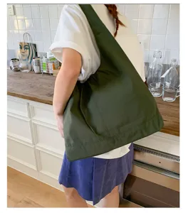 Detailed lifestyle shot of a dark green canvas shoulder tote bag in kitchen setting.