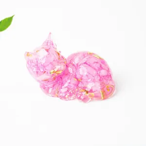 Close-up detail of pink crystal resin cat figurine with shimmering gold foil accents.