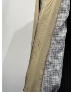 Dettaglio di giacca da donna con cerniera metallica e fodera a quadri elegante.