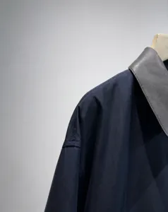 Dettaglio giacca corta blu scuro con colletto in PU grigio a contrasto e design minimalista.