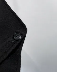 Close-up detail of premium women's black wool cashmere coat showing button craftsmanship.