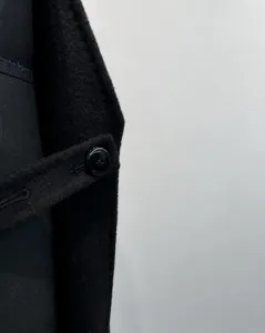 Close-up detail of luxury black cashmere wool coat fabric and button design, elegant minimal style.