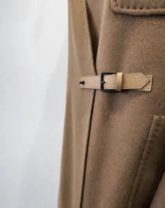 Detail shot of women's short cashmere coat with stylish leather belt and metal buckle.
