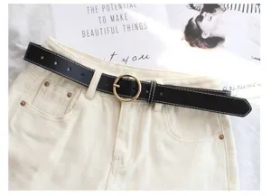 Women fashion black leather belt with gold round buckle and white stitching, chic denim accessory.