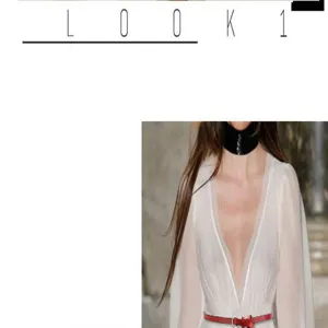 Detail view of a slim red leather belt with a delicate metal buckle worn on a dress.