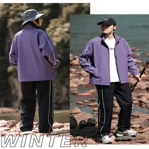 Outdoor couple tracksuit detail shot, purple zip jacket and black pants with white side stripes.