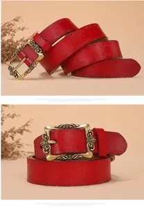 Close up of red embossed leather belt with vintage bronze buckle, detailed retro floral pattern.