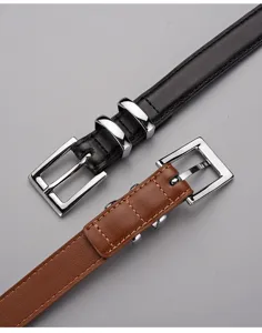 Détail de ceinture fine en cuir avec boucle carrée argentée et coutures délicates.