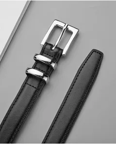 Détail de ceinture en cuir noir avec boucle métallique argentée brillante et doubles passants.