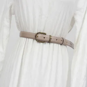 Detail view of a women's taupe genuine leather belt with ornate vintage metal buckle.