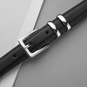 Gros plan de la fine ceinture élégante en cuir noir avec boucle ardillon en métal argenté.