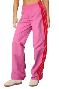 Dettaglio dei pantaloni della tuta rosa da donna con strisce laterali rosse in evidenza.