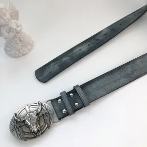 Western vintage leather belt with bull skull buckle and metal studs, detail view.