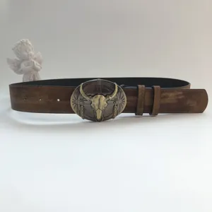Vintage western style brown leather belt featuring a detailed metal bull skull buckle close up view