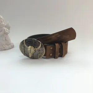Detail shot of vintage brown leather belt with metal bull skull buckle, western retro style.