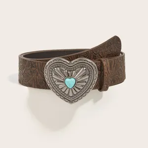 Detailed close-up of brown embossed western vintage leather belt with ornate silver heart buckle.