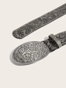 Detailed shot of a vintage western embossed leather belt with ornate floral oval metal buckle.