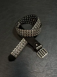 Black punk rock multi-grommet leather belt, stylish metallic double-prong buckle detail.