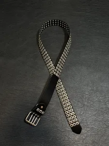 Detailed view of the punk rock black leather belt with multiple metal grommets and double buckle.