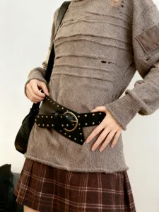 Détail d'une large ceinture en cuir clouté style punk avec une boucle métallique.