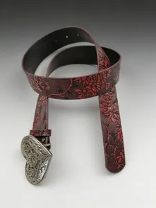 Vintage western leather belt with embossed floral pattern and unique heart metal buckle.