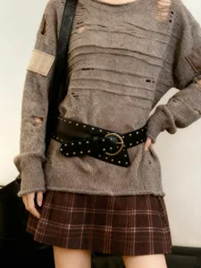 Vue détaillée de la large ceinture à rivets style punk pour femmes avec pull usé stylé.